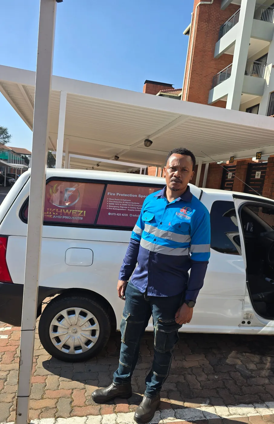 A Likhwezi Fire and Projects technician in branded workwear beside the company vehicle